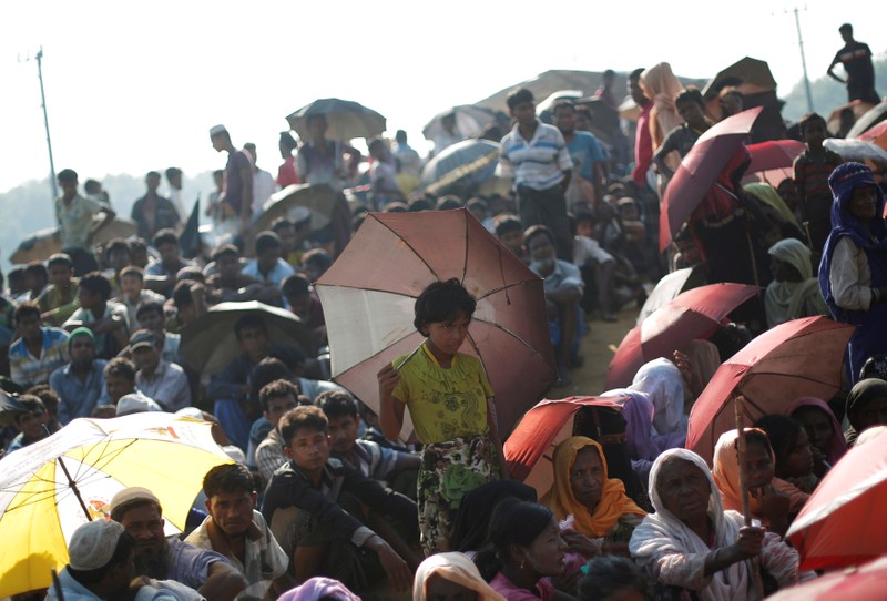 Rohingya refugees sit as they wait to receive humanitarian aid at Balu Khali refugee camp