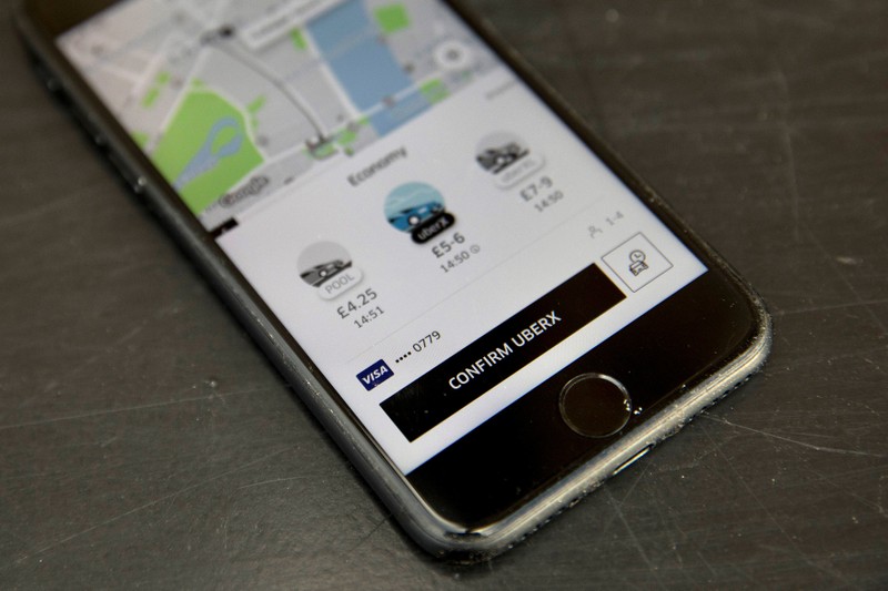 A photo illustration shows the Uber app on a mobile telephone, as it is held up for a posed photograph, in London