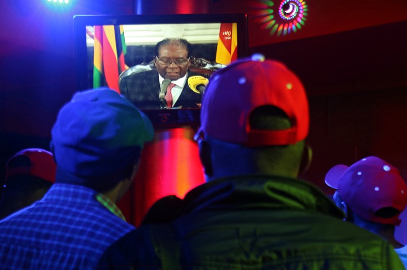 People watch as Zimbabwean President Robert Mugabe addresses the nation on television, at a bar in Harare