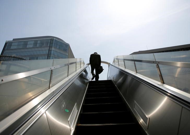 FILE PHOTO: A businessman rides on an escalator in Tokyo's business district
