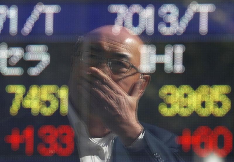 FILE PHOTO: A man is reflected in an electronic stock quotation board outside a brokerage in Tokyo