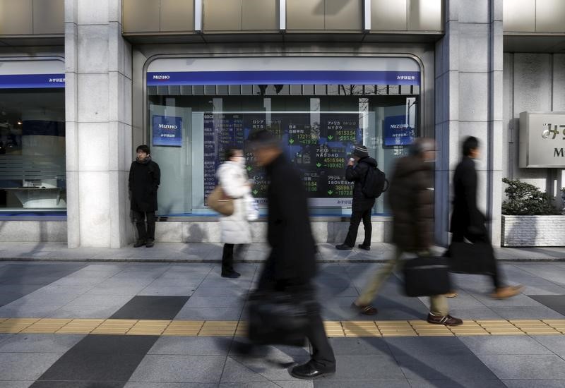 A pedestrian looks an electronic board showing the stock market indices of various countries outside a brokerage in Tokyo