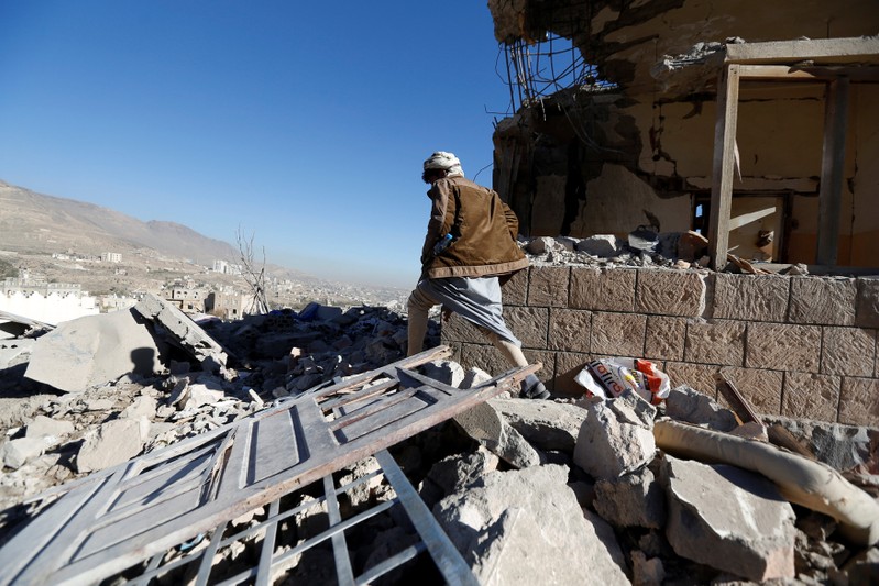 Man walks past a destroyed house at the site of air strikes in Sanaa