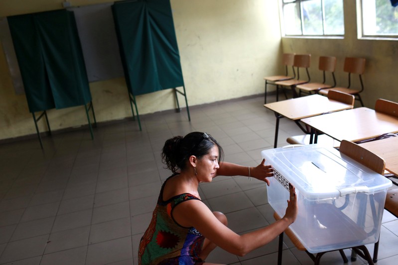 A woman puts a sticker on a ballot box at a voting station ahead upcoming Chile's presidential election on December 17, in Santiago