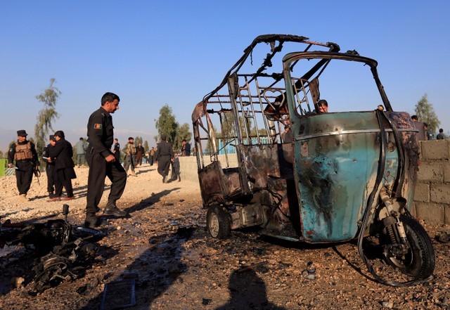 Afghan police inspect the site of a suicide attack on the outskirts of Jalalabad