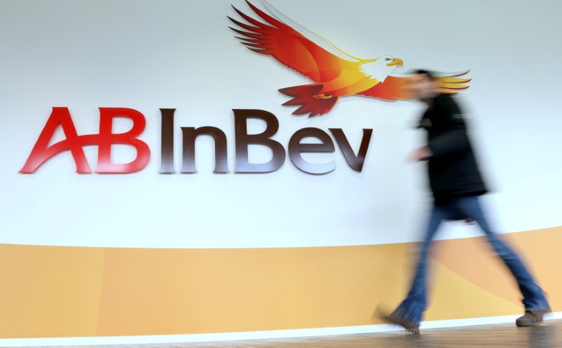 FILE PHOTO: A man walks past the logo of Anheuser-Busch InBev at the brewer's headquarters in Leuven