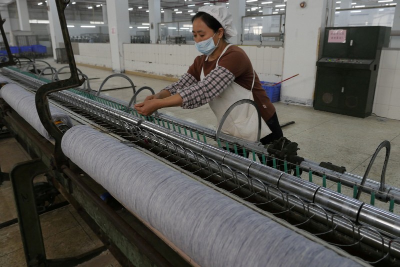 FILE PHOTO: A worker disentangles wool yarn at a spinning machine at a factory owned by Hong Kong's Novetex Textiles Limited in Zhuhai City, Guangdong Province, China