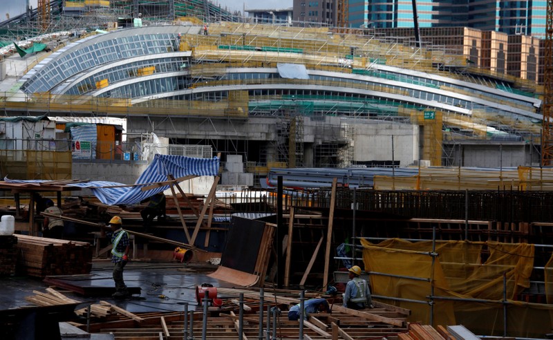 FILE PHOTO: Laborers work in front of West Kowloon Terminus, under construction for the Guangzhou-Shenzhen-Hong Kong Express Rail Link, in Hong Kong