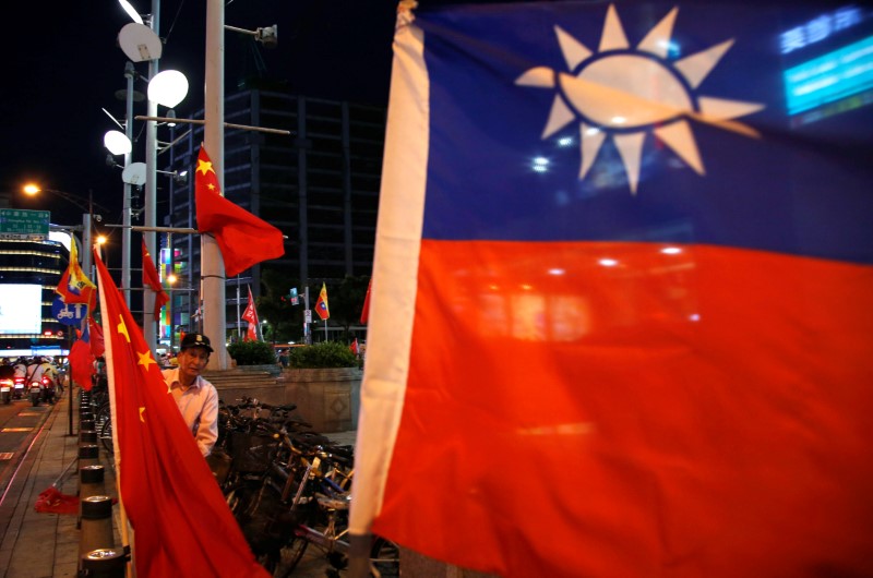 FILE PHOTO: A pro-China supporter adjusts a China national flag during a rally calling for peaceful reunification, days before the inauguration ceremony of President-elect Tsai Ing-wen, in Taipei