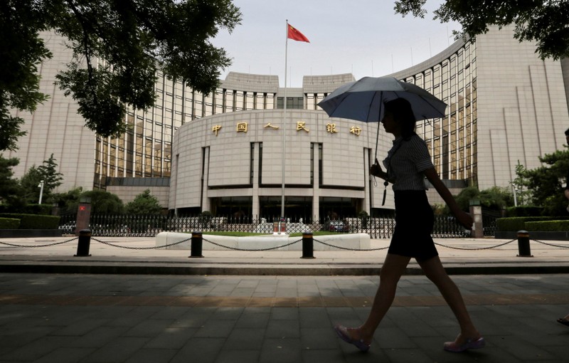 FILE PHOTO: A woman walks past the headquarters of the PBOC in Beijing