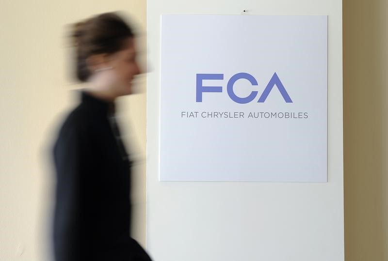 A woman walks past a logo of Fiat Chrysler Automobiles (FCA) in Turin