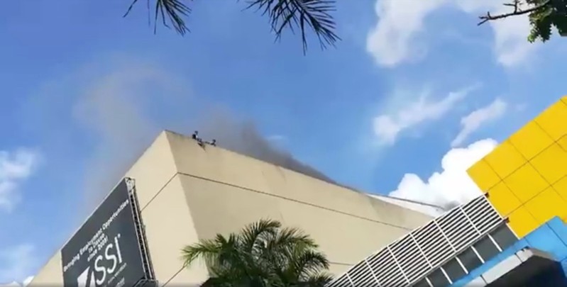 People are seen on the roof of a building as smoke rises during a fire in Davao, the Philippines