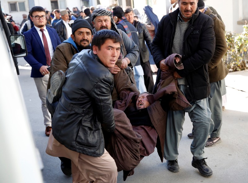 People carry a mourning man at a hospital after a suicide attack in Kabul