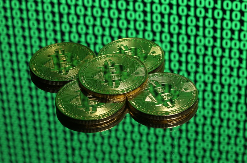 FILE PHOTO: Bitcoin tokens are seen placed on a monitor that displays binary digits in this illustration picture