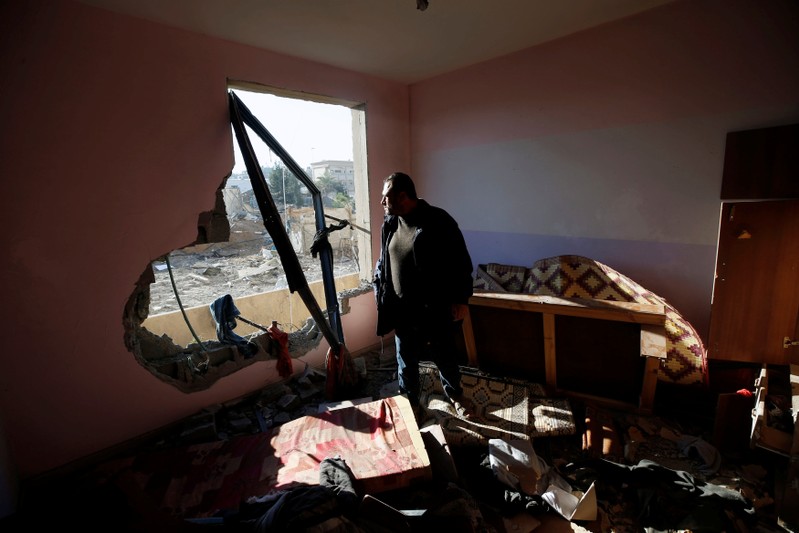A Palestinian man looks out of his apartment that was damaged in an Israeli airstrike at a nearby militant target in the northern Gaza Strip