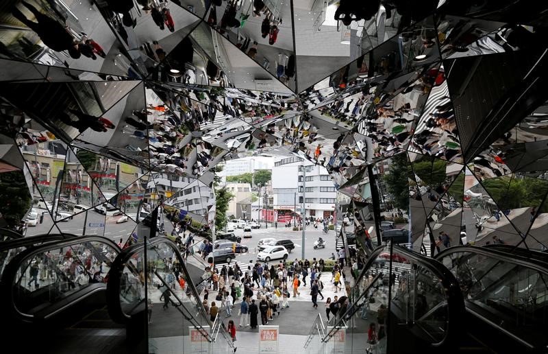 People are reflected in mirrors at an entrance of a shopping complex in Tokyo