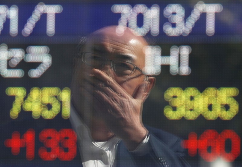 A man is reflected in an electronic stock quotation board outside a brokerage in Tokyo