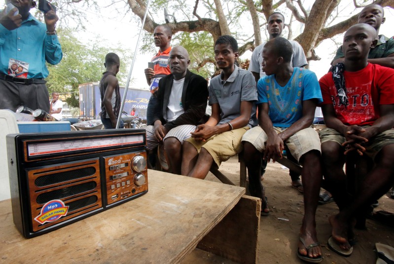 Supporters of George Weah, former soccer player and presidential candidate of Coalition for Democratic Change (CDC), listen to the announcement of the presidential election results on the radio, in Monrovia, Liberia