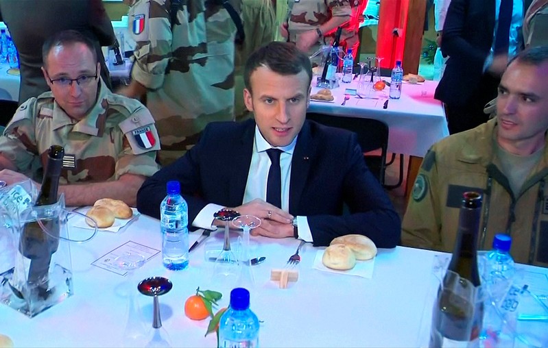 French President Emmanuel Macron, seen in this still image taken from video, sits with French military forces during a visit with troops who participate in the Operation Barkhane in Niamey