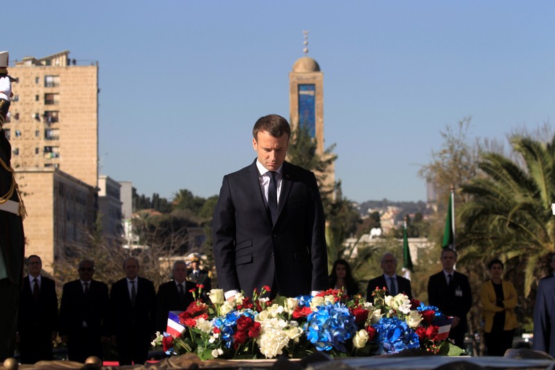 French President Emmanuel Macron bows during a wreath-laying ceremony at the Martyrs Monument in Algiers