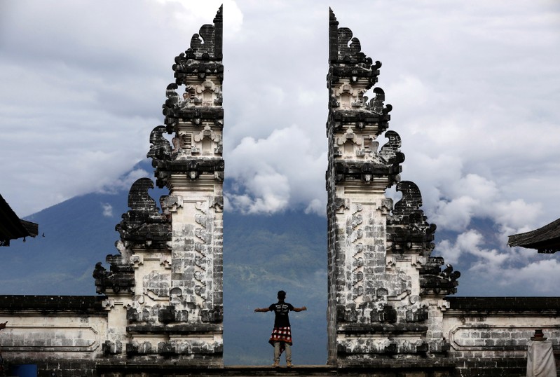 A Balinese man stands at the gate of Lempuyang temple looking towards Mount Agung volcano, in Karangasem Regency, Bali