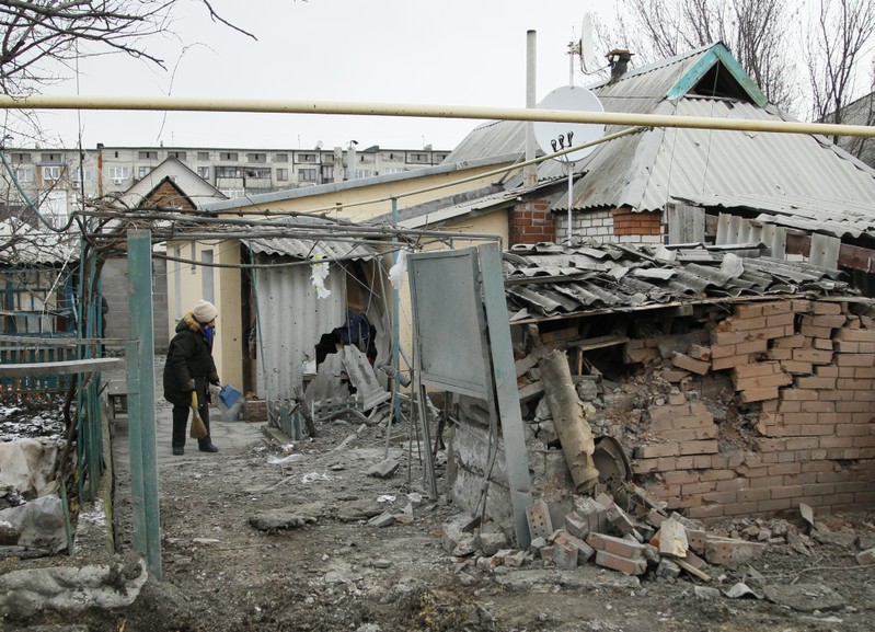 A woman cleans up debris near her house damaged by recent shelling in the rebel-held town of Yasynuvata