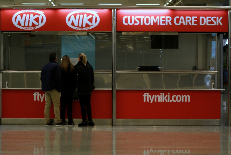 People stand in front of an empty Niki customer care desk at Palma de Mallorca airport