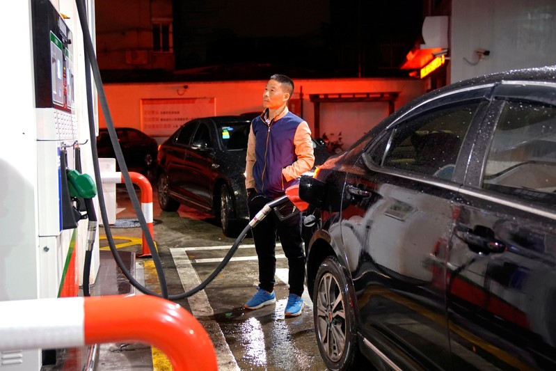 A driver looks at the price as he fills the tank of his car at a gas station in Shanghai