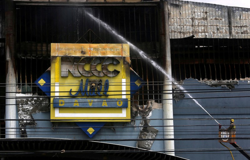 A fireman uses a water hose at a shopping mall hit by fire in Davao