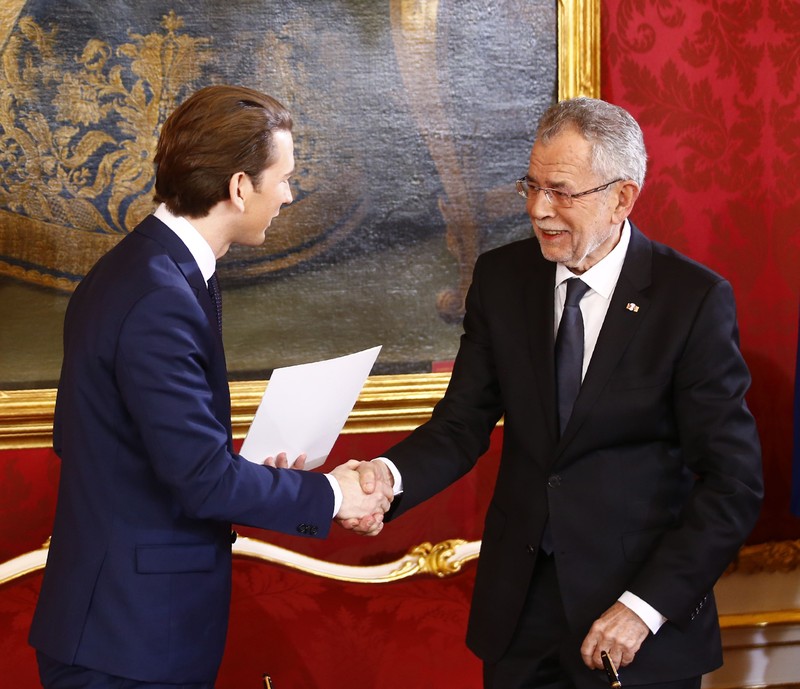 Austrian president van der Bellen and head of the People's Party Kurz shake hands during the swearing-in ceremony of the new government in Vienna