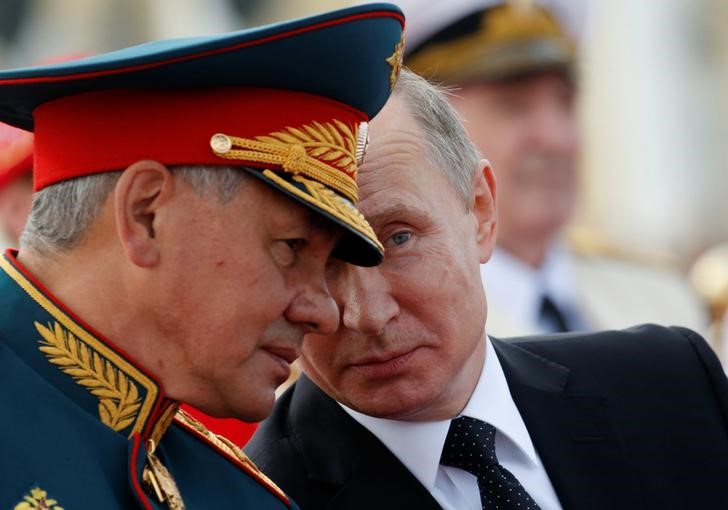 Russian President Vladimir Putin speaks with Defence Minister Sergei Shoigu as they attend the Navy Day parade in St. Petersburg