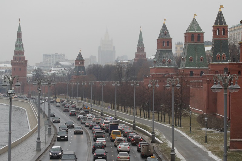 Vehicles drive past the wall and towers of the Kremlin in central Moscow