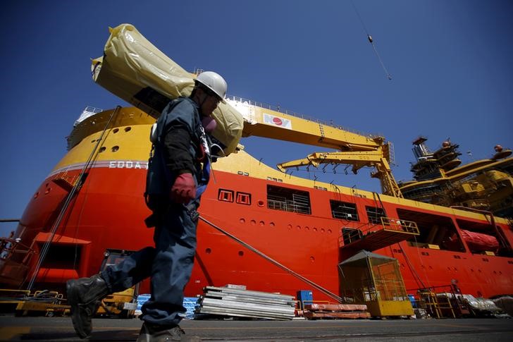 FILE PHOTO: A worker carries construction materials as he walks past a ship which is currently under construction at Hyundai Heavy Industries' Shipyard in Ulsan, South Korea