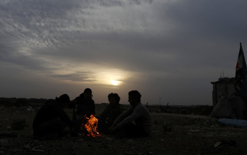 Free Syrian Army fighters sit together around a bonfire in the rebel-held town of Dael