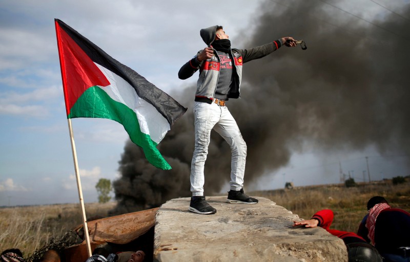 Palestinian demonstrator uses a slingshot to hurl stones towards Israeli troops during clashes at a protest near the border with Israel in the east of Gaza City