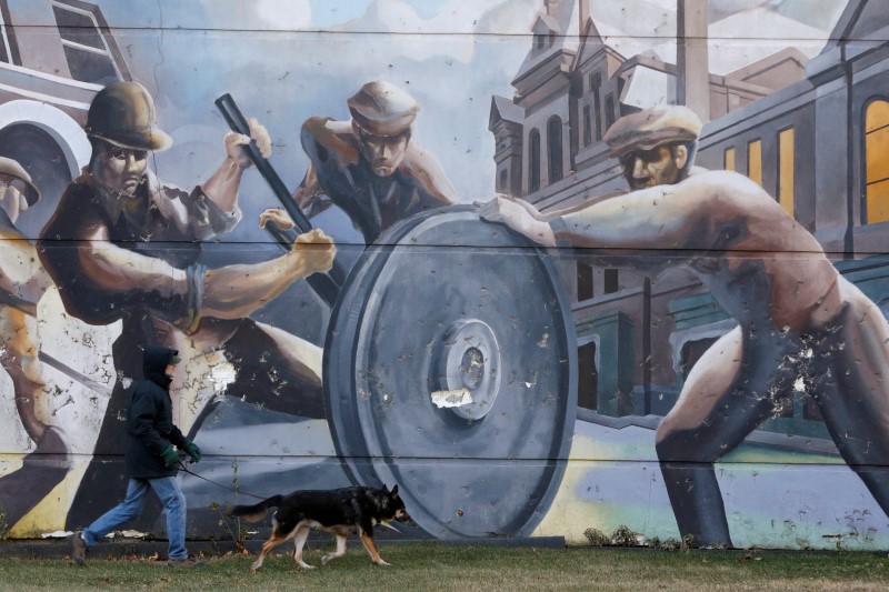 A man walks his dog past a mural depicting factory workers in Chicago's historic Pullman neighborhood.