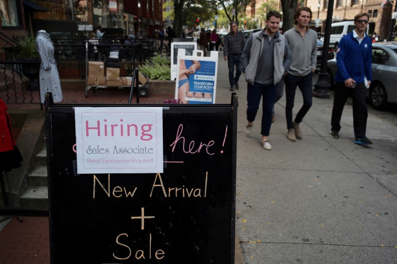 FILE PHOTO: Pedestrians pass a sign advertising a sale and a job opening at a shop on Newbury Street in Boston