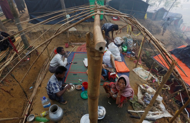 FILE PHOTO: A Rohingya refugee family eats as they sit inside their semi constructed shelter at Kutupalong refugee camp near Cox's Bazar