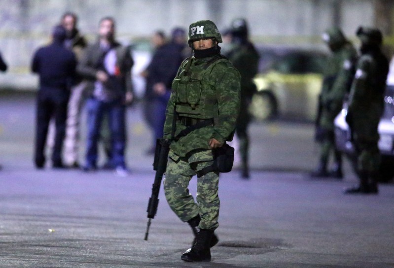 A soldier stands guard next to a crime scene in the municipality of San Nicolas de los Garza