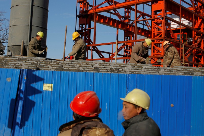 FILE PHOTO: Workers lay bricks to build a wall around a construction site in Beijing