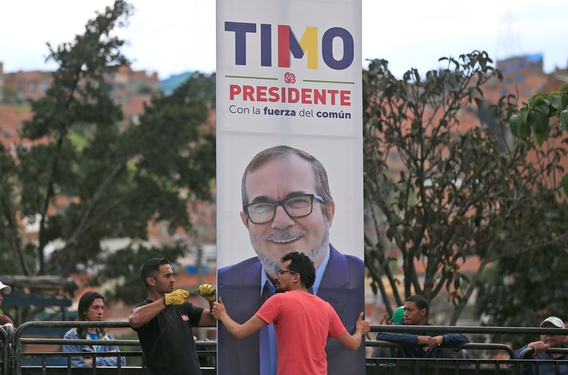 Men place a banner of the FARC leader Rodrigo Londono, known as Timochenko, during the presentation as a candidate for the presidency of Colombia in Bogota