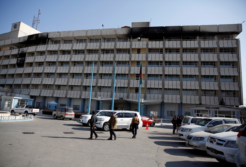 Afghan security guards walk in front of the Intercontinental Hotel after an attack in Kabul
