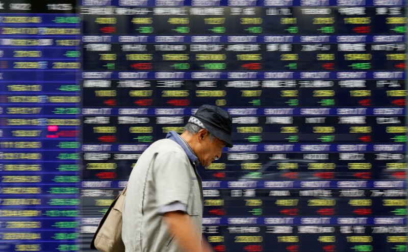 A man walks past an electronic stock quotation board outside a brokerage in Tokyo