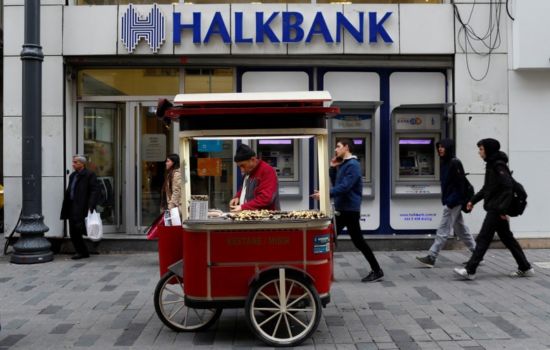 A street vendor sells roasted chestnuts in front of a branch of Halkbank in central Istanbul