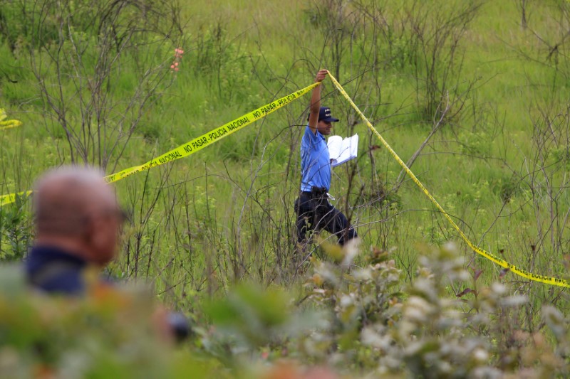 FILE PHOTO: A police officer cordons off a clandestine cemetery that was recently discovered in El Lolo neighbourhood, on the outskirts of Tegucigalpa