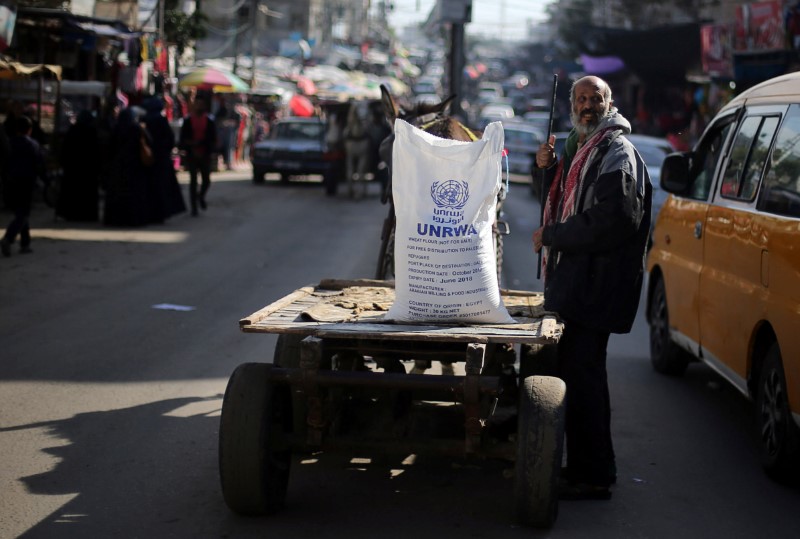 A Palestinian man stands next to a cart carrying a flour sack distributed by UNRWA in Khan Younis refugee camp in the southern Gaza Strip