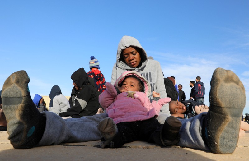 A migrant rests with her children at a naval base after they were brought back by Libyan coast guards in Tripoli