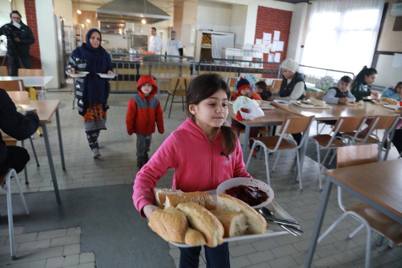 Sonya, 8, daughter of Afghan refugee Najibullah, carries food at the camp for refugees and migrants in the Belgrade suburb of Krnjaca