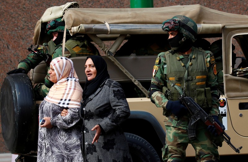 Women walk by special forces soldiers guarding the National Election Authority, which is in charge of supervising the 2018 presidential election in Cairo