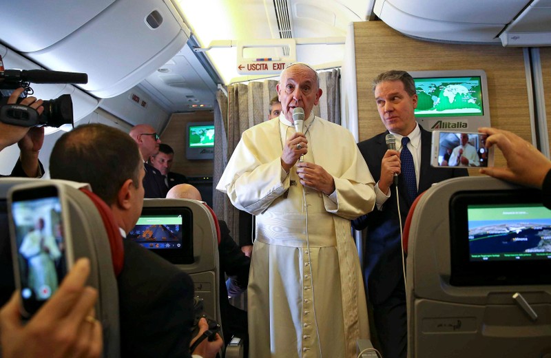 Pope Francis speaks to reporters onboard the plane for his trip to Chile and Peru